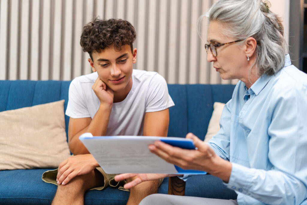 Teenage boy is listening attentively to his therapist while looking at a treatment plan during a therapy session at the psychologist's office