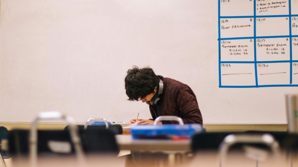 Photo of a teenager in a classroom huddled over desk, deep in work. For teen OCD and anxiety treatment in North Carolina contact BlueRock today.