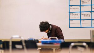 Photo of a teenager in a classroom huddled over desk, deep in work. For teen OCD and anxiety treatment in North Carolina contact BlueRock today.